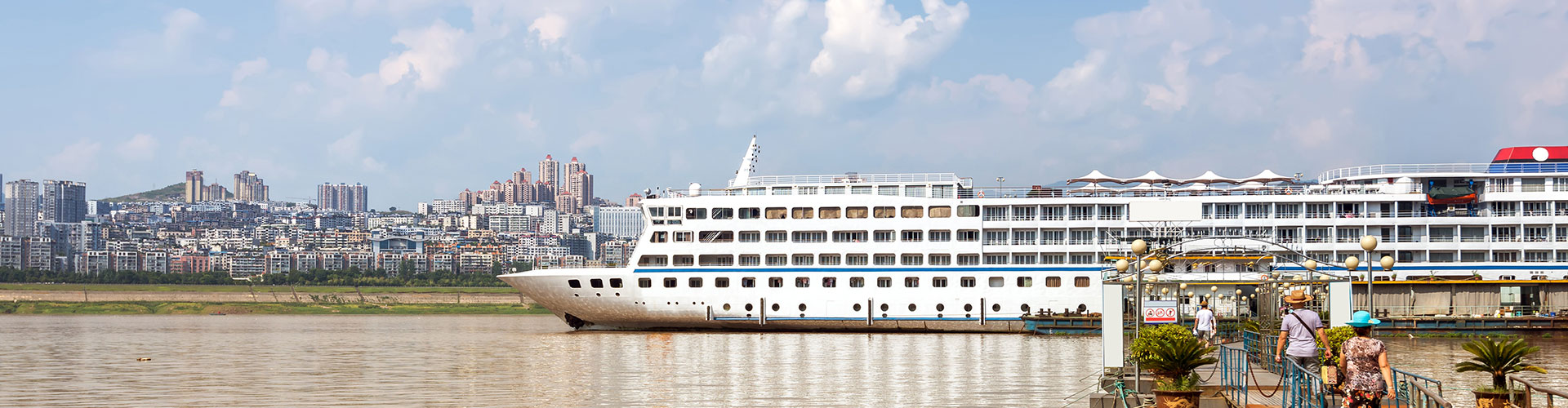 Large white multi-deck cruise ship moored beside a riverside city